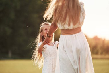 Beyaz elbiseli. Anne ve kızı dışarıda, tarlada yürüyüş yaparak hafta sonunun tadını çıkarıyorlar. Güzel doğa..
