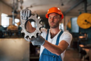 Motorun bir parçası. Üniformalı adam prodüksiyonda çalışıyor. Endüstriyel modern teknoloji.