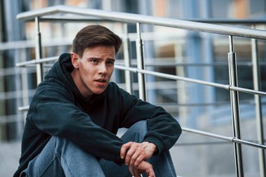 Siyah elbiseli gencin portresi merdivenlerde oturuyor ve dinleniyor..