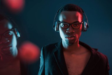 Kulaklıkla müzik dinlemeyi seviyorum. Gözlüklü. Fütürist neon ışıkları. Stüdyodaki Afrikalı Amerikalı genç adam..