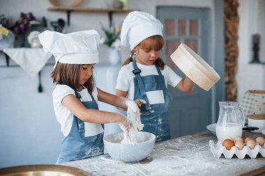 Kullanılmış elek. Beyaz şef üniformalı aile çocukları mutfakta yemek hazırlıyorlar..