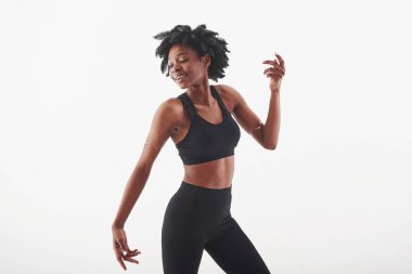 İlginç bir poz. Stüdyoda beyaz arka planda güzel bir Afro-Amerikan kadın var..