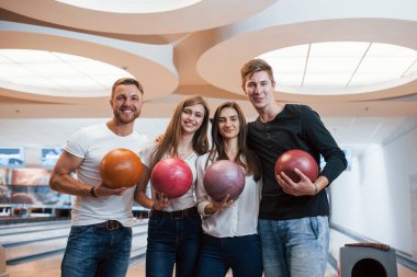 Kameraya gülümseyen güzel modern insanlar. Genç neşeli arkadaşlar hafta sonları bowling kulübünde eğleniyorlar..