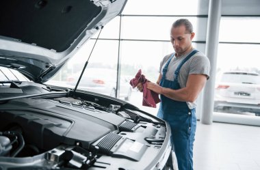 Bela arıyorum. Mavi üniformalı adam bozuk arabayla çalışıyor. Onarımlar yapılıyor.