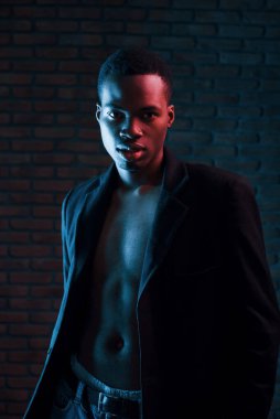 Vücudu gösteriyor. Fütürist neon ışıkları. Stüdyodaki Afrikalı Amerikalı genç adam..