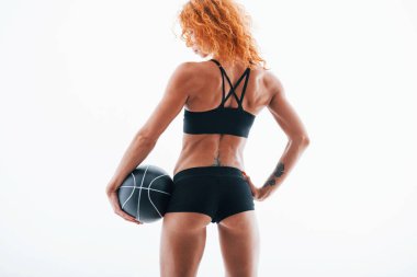 Futbol toplu bir kamera için poz vermek. Parçacık görünümü. Kızıl saçlı kadın vücut geliştirici beyaz arka planda stüdyoda..