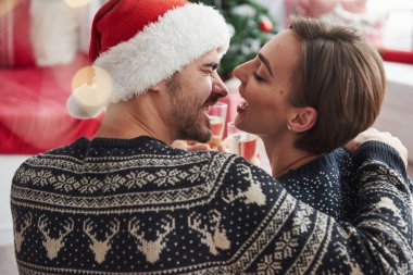 Neşeli insanlar. Yeni yılı kutluyoruz. Kapı çalan gözlükler. Tatil kıyafetleri içinde güzel bir çift oturur ve birbirlerine sarılırlar. Fotoğraf arkadan..