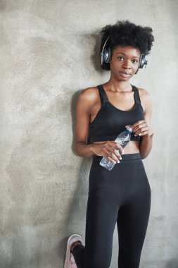 Bir şişe taze suyla. Spor yaptıktan sonra spor kıyafetli Afrikalı Amerikalı bir kızın portresi..