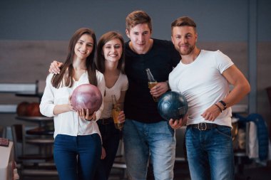 Ellerinde alkolle. Genç neşeli arkadaşlar hafta sonları bowling kulübünde eğleniyorlar..