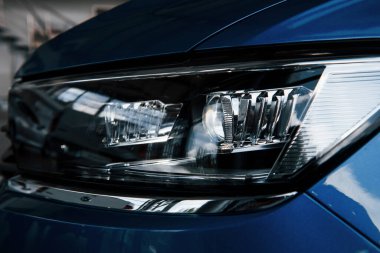 Yepyeni modern mavi arabanın ön tarafı. Galeriye park ettim. Farlardaki yansıma..