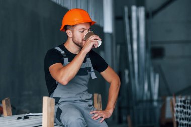 Bir bardak içkiyle. Yemek molası. Fabrikada sanayi işçisi. Turuncu şapkalı genç teknisyen..