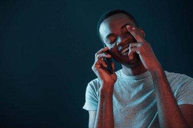 Telefon kullanarak sohbet ediyorlar. Fütürist neon ışıkları. Stüdyodaki Afrikalı Amerikalı genç adam..