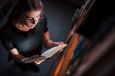Hava görüntüsü. Kütüphanede kitaplarla dolu bir kız öğrenci var. Eğitim kavramı.