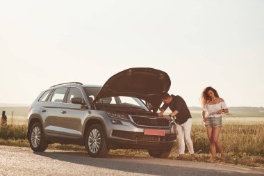 Meşgul bir işçi. Adam kıvırcık saçlı bir kızın arabasını tamir ediyor. Mekanik yardım.