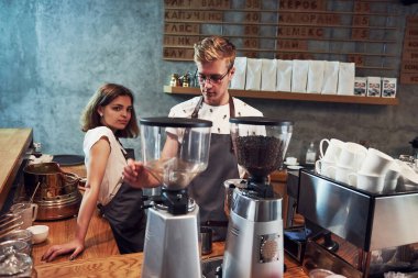 Kahve makinesinin arkasında. İçeride iki genç işçi var. İş ve hizmet kavramı.