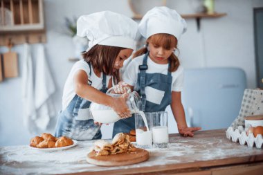 Kurabiyeler hazır. Beyaz şef üniformalı aile çocukları mutfakta yemek hazırlıyorlar..