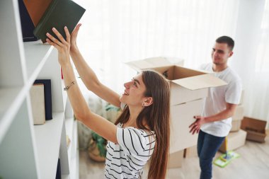 Her kitap doğru yerde olmak zorunda. Yeni dairelerinde neşeli genç bir çift. Taşınma kavramı.