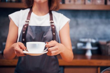 Siparişinizi alın. İçinde beyaz bardakta taze içki var. Genç bayan kafe çalışanı içeride. İş ve hizmet kavramı.