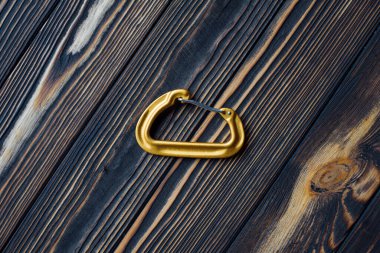 Güvenlik aleti. Tırmanma ekipmanlarının izole edilmiş fotoğrafı. Karabinanın bir parçası ahşap masada yatıyor..