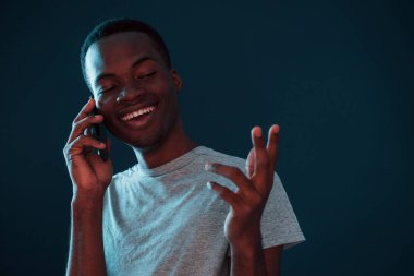 Telefon kullanarak sohbet ediyorlar. Fütürist neon ışıkları. Stüdyodaki Afrikalı Amerikalı genç adam..