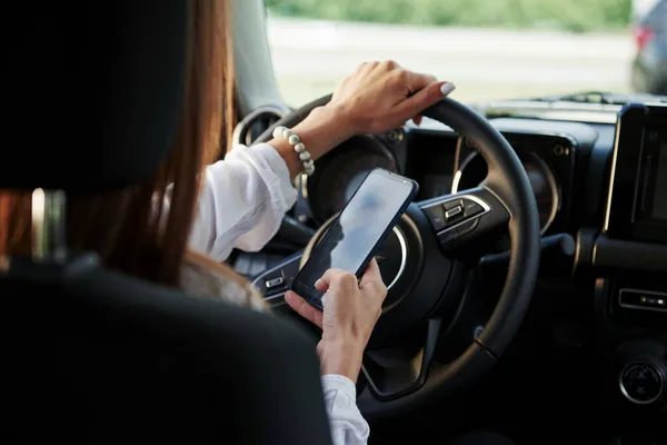 Folosind Smartphone Vedere Particulară Femeii Care Conduce Mașină Nouă Modernă — Fotografie, imagine de stoc