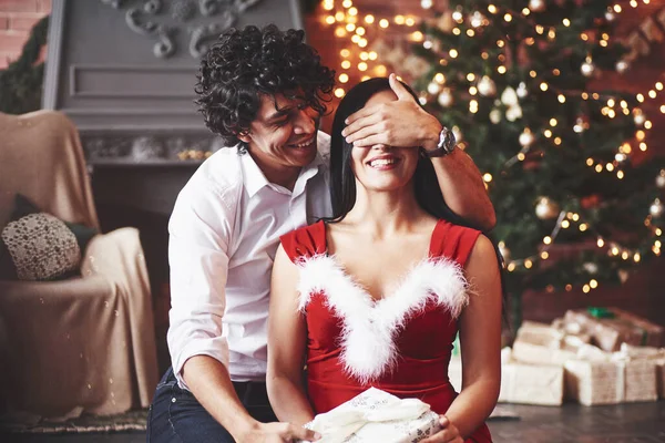 準備はいいか 目を覆う赤いドレスの女性と意志受け取っクリスマスギフトからボーイフレンド — ストック写真