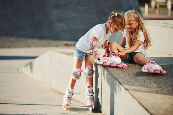 暖かい天気 極端なスポーツのためのランプで ローラースケートを持つ2人の女の子屋外で楽しいです — ストック写真