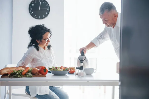 熱いお茶 台所で野菜を使った料理を作る白いシャツを着た男と妻 — ストック写真