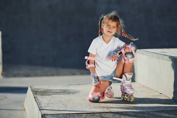 かわいいです女の子とともにローラースケート屋外で座っています極端なスポーツのためにランプ — ストック写真