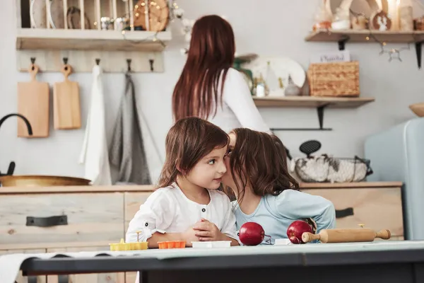 Dzieci Potajemnie Rozmawiają Sobą Kuchni Podczas Gdy Mama Przygotowuje Kolację — Zdjęcie stockowe