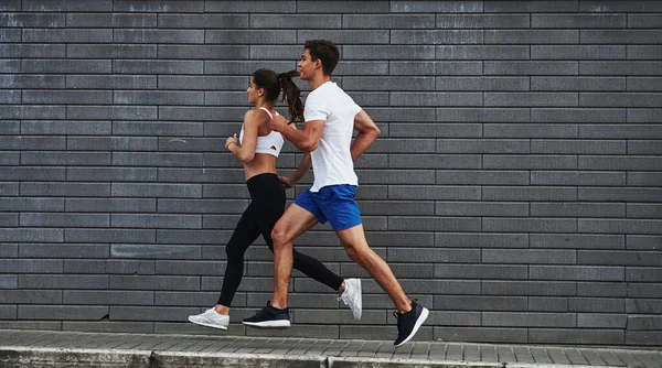健康的生活方式男人和女人每天都很健康 白天在城中靠近砖墙跑步 — 图库照片