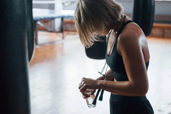 Şişeyi Suyla Açıyorum Spor Salonundaki Siyah Kum Torbasının Yanındaki Kadın — Stok fotoğraf