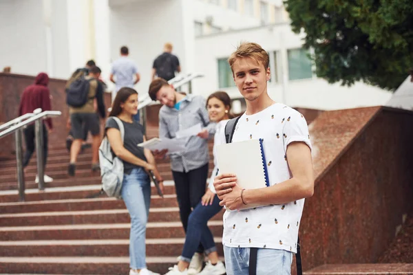 有人在镜头前摆姿势一群穿着休闲装的年轻学生白天在大学附近 — 图库照片