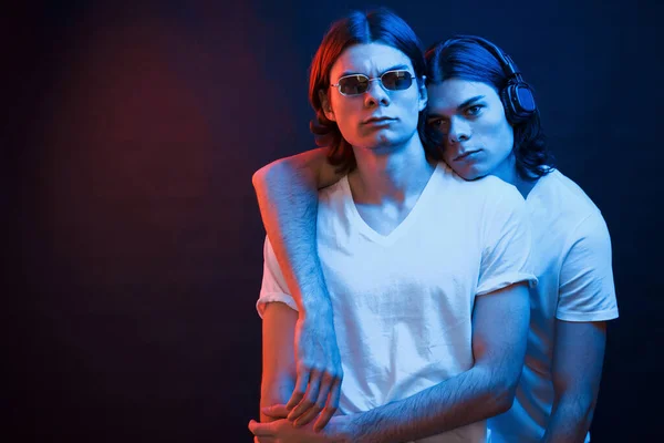 友好的な抱擁 双子の兄弟の肖像画 ネオンで暗いスタジオで撮影されたスタジオ — ストック写真