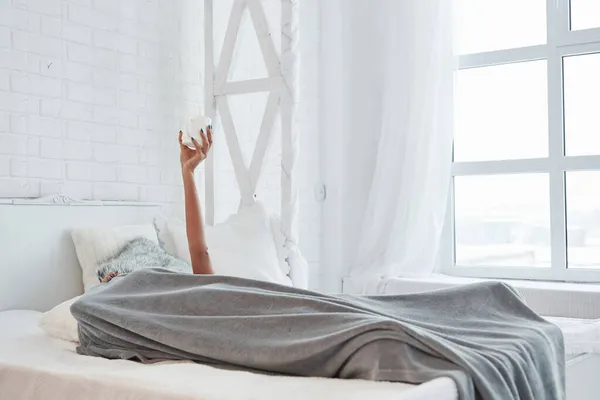 Γυναίκα Ξαπλωμένη Κάτω Από Την Κουβέρτα Και Σηκώνοντας Χέρι Λευκό — Φωτογραφία Αρχείου