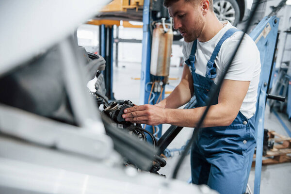 Almost done. Employee in the blue colored uniform works in the automobile salon.