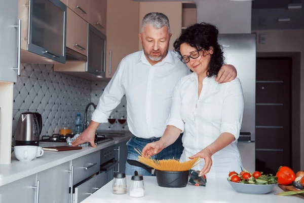 私たちのために 台所で野菜を使った料理を作る白いシャツを着た男と妻 — ストック写真