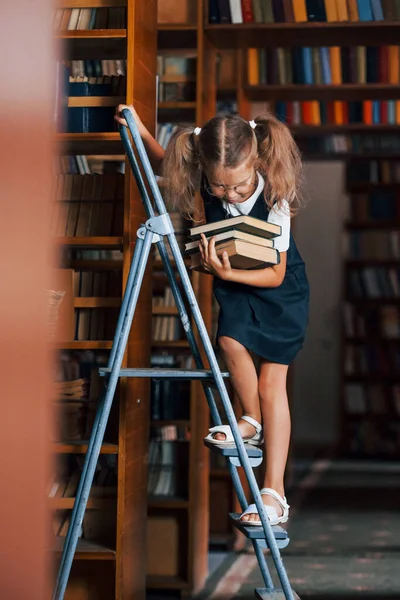 Schulmädchen Auf Der Leiter Der Bibliothek Voller Bücher Bildungskonzept — Stockfoto