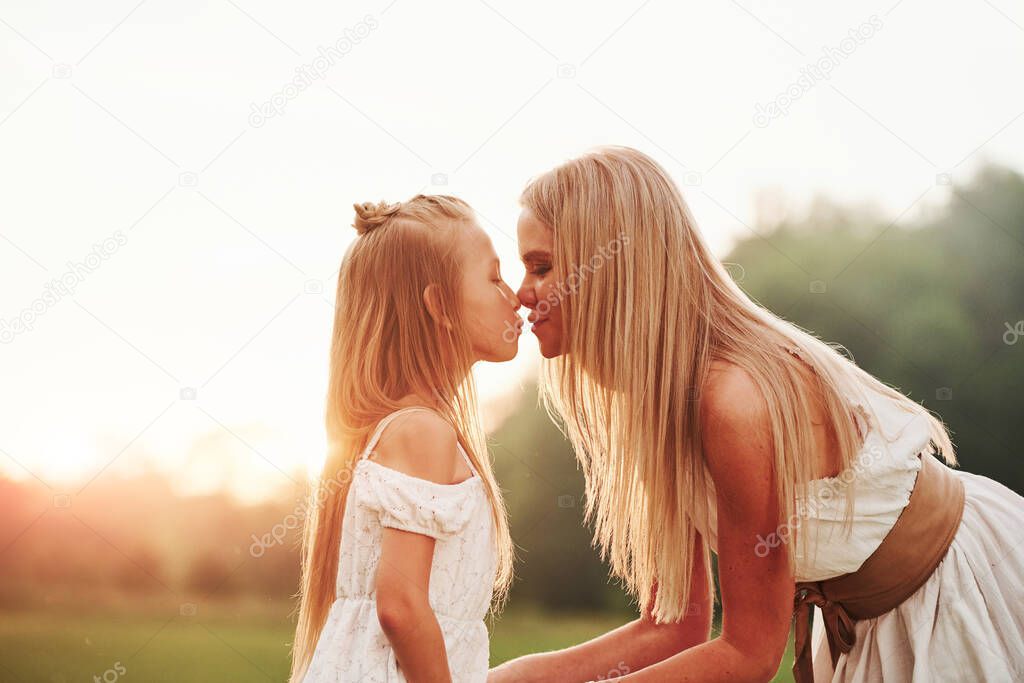 Blurred background. Mother and daughter enjoying weekend together by walking outdoors in the field. Beautiful nature.