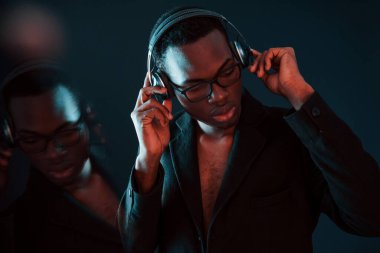 Kulaklıkla müzik dinlemeyi seviyorum. Gözlüklü. Fütürist neon ışıkları. Stüdyodaki Afrikalı Amerikalı genç adam..