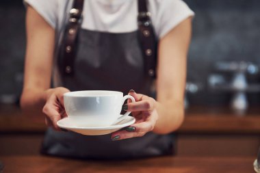 Siparişinizi alın. İçinde beyaz bardakta taze içki var. Genç bayan kafe çalışanı içeride. İş ve hizmet kavramı.