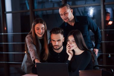 Resmi kıyafetler. Genç iş adamlarından oluşan bir ekip gece ofiste projeleri üzerinde çalışıyor..