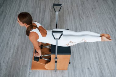 Hava görüntüsü. Sağlıklı merkezde zayıf vücutlu, kendine güvenen genç bir kadın özel ekipman kullanarak egzersiz yapıyor..