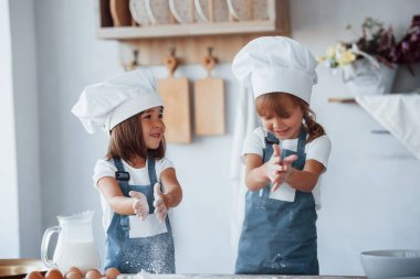 Beyaz şef üniformalı aile çocukları mutfakta yemek hazırlıyorlar..