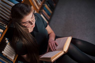 Üst Manzara. Kütüphanede kitaplarla dolu bir kız öğrenci var. Eğitim kavramı.