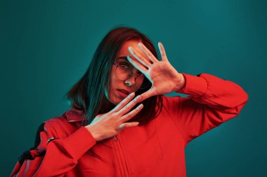 El hareketleriyle. Stüdyo içeride neon ışıkla çekiliyor. Güzel bir genç kızın portresi.