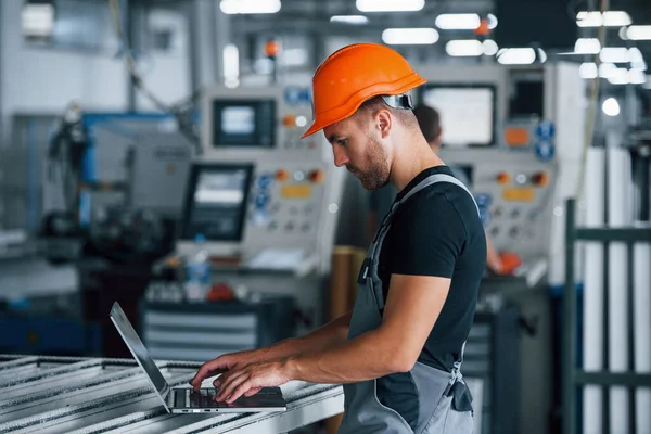 Modern Laptop Klavyede Yazıyorum Fabrikada Sanayi Işçisi Turuncu Şapkalı Genç — Stok fotoğraf