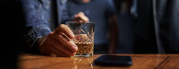 Närbild Glas Med Alkohol Människans Hand Håller Den Smartphone Bordet — Stockfoto