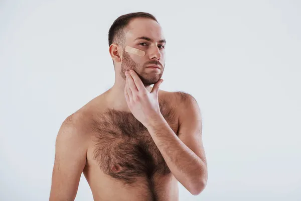 ひげを剃るときに何が起こるかここに注意していない 男とともに裸胸スタンドに白背景でザスタジオ — ストック写真