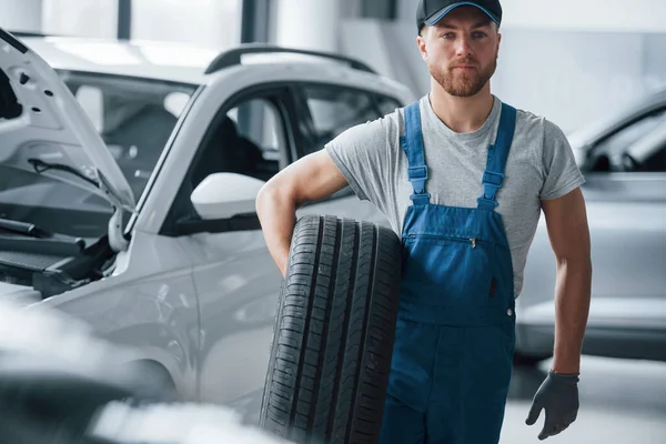 Diğer arabanın kaputu açıldı. Tamirhanede lastik tutan bir tamirci. Kış ve yaz lastiklerinin değiştirilmesi.